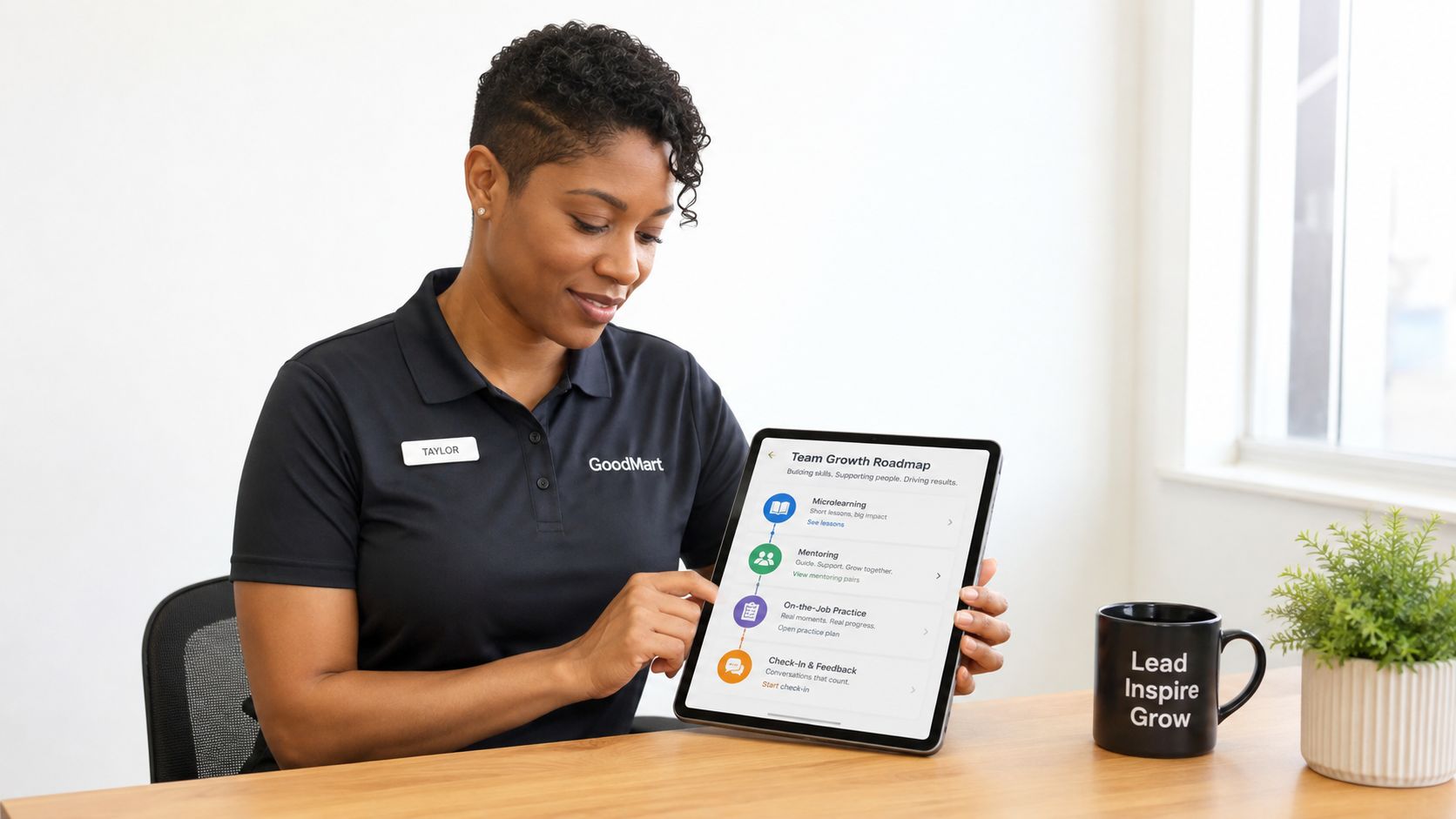 A professional woman in a GoodMart uniform reviews a team growth roadmap on her tablet at a desk.